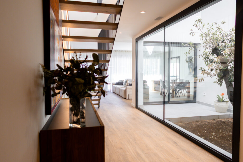 Pasillo con gran ventanal que mejora la eficiencia energética aprovechando luz natural en una vivienda diseñada por NEXT Arquitectura.