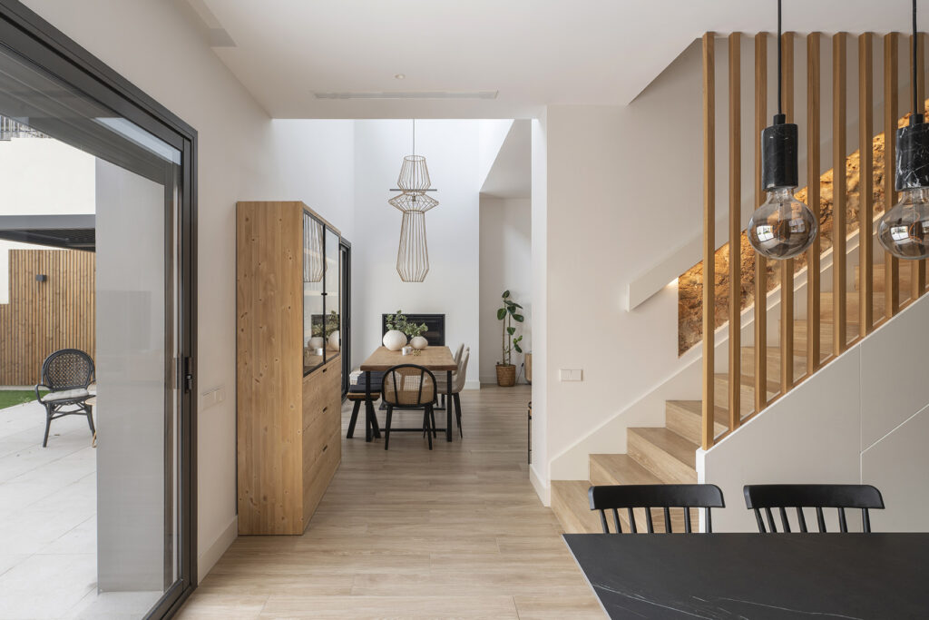 Resultado de una reforma integral con diseño cálido y arquitectura luminosa, uniendo comedor, escalera y patio en un espacio contemporáneo.