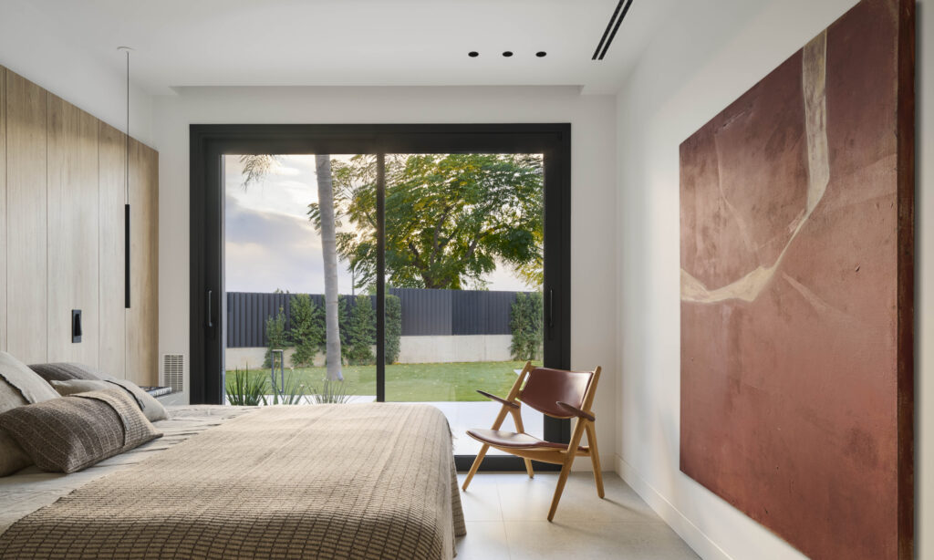 Dormitorio con suelo cerámico claro y diseño de interiores contemporáneo, integrado con grandes ventanales y mobiliario neutro.