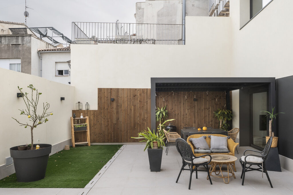 Patio exterior en vivienda urbana con zonas diferenciadas de estar y vegetación, pensado como espacio exterior habitable durante todo el año.