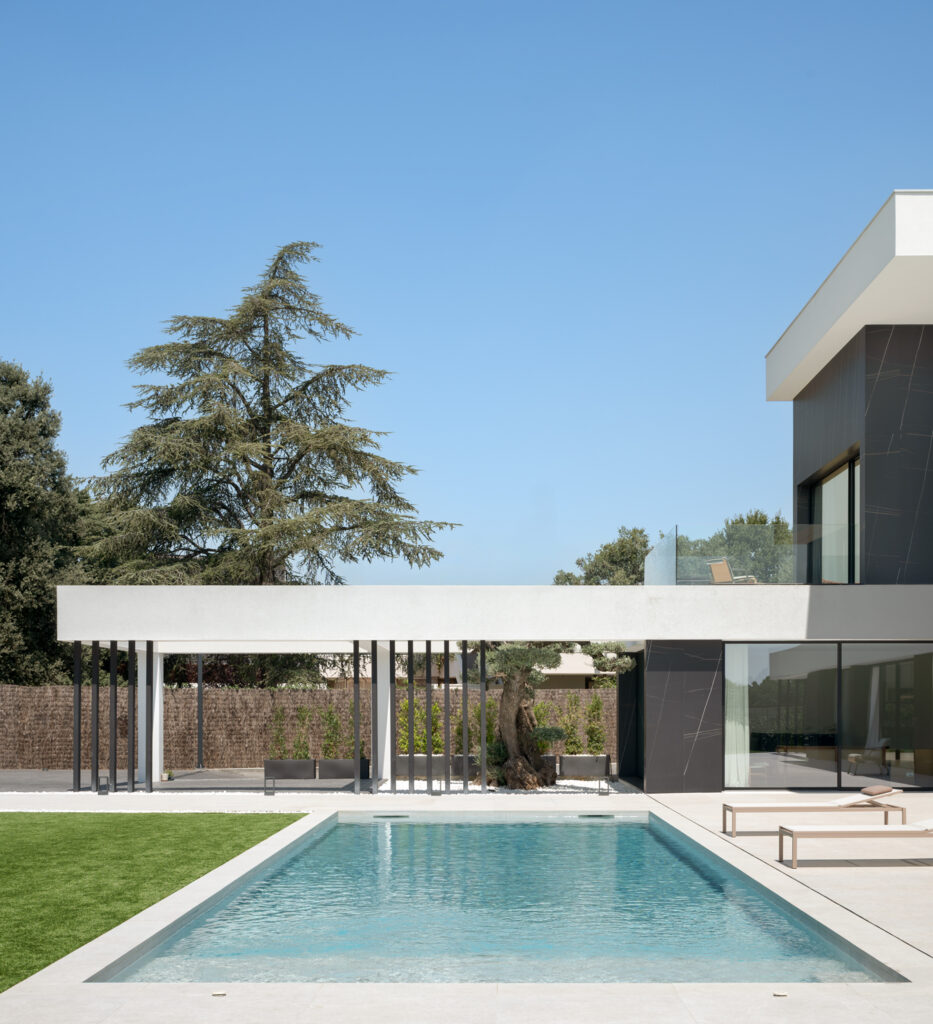 Espacio exterior de una vivienda unifamiliar con piscina integrada y terraza conectada al interior, diseñada para un uso cotidiano confortable.