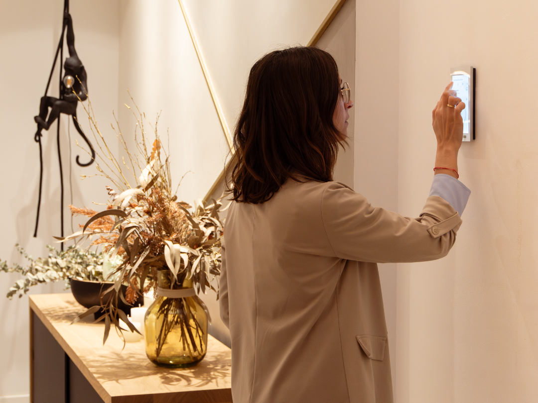 Persona regulando un sistema de domótica en una vivienda, control de iluminación y climatización integrado en el diseño arquitectónico del espacio.