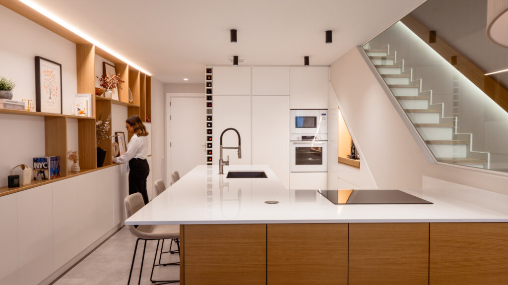 Tendencias de diseño 2026 en casa: cocina con isla central, iluminación integrada y combinación de madera y superficies continuas para un uso cotidiano funcional.