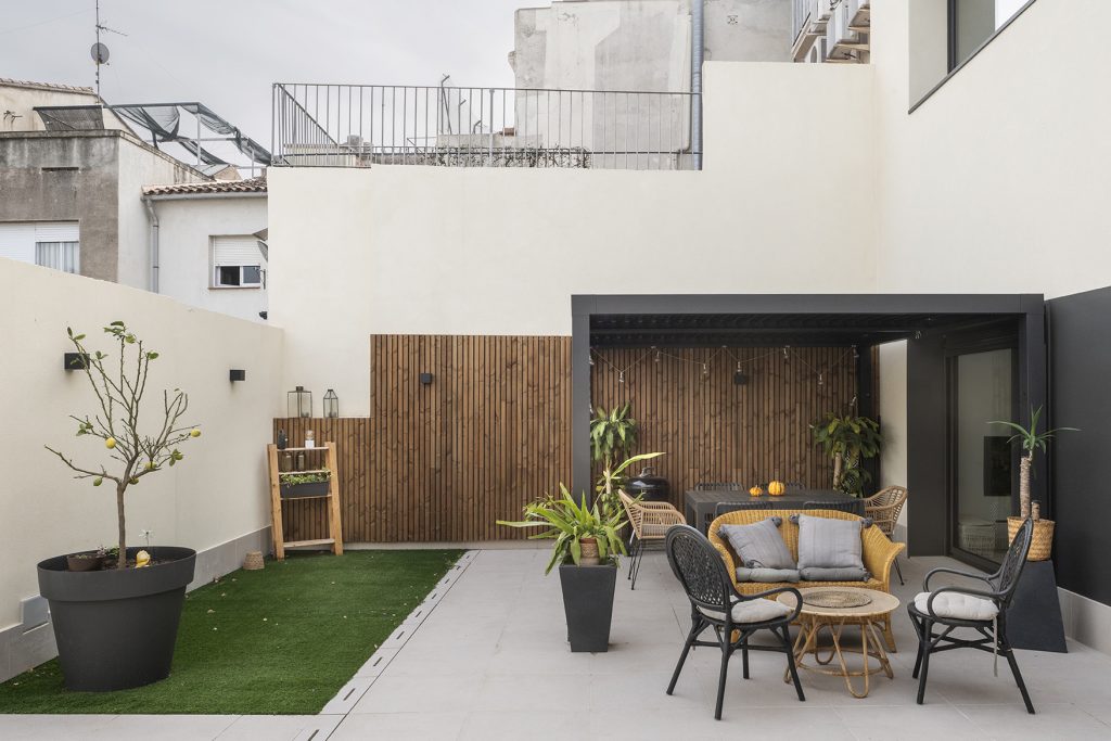Patio exterior en vivienda urbana con zonas diferenciadas de estar y vegetación, pensado como espacio exterior habitable durante todo el año.