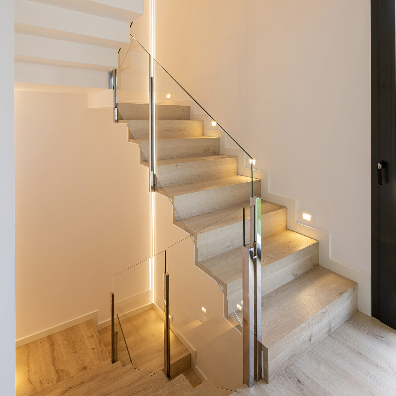 Iluminación integrada en una escalera interior, ejemplo de iluminación arquitectónica que mejora la seguridad y el confort en la vivienda.