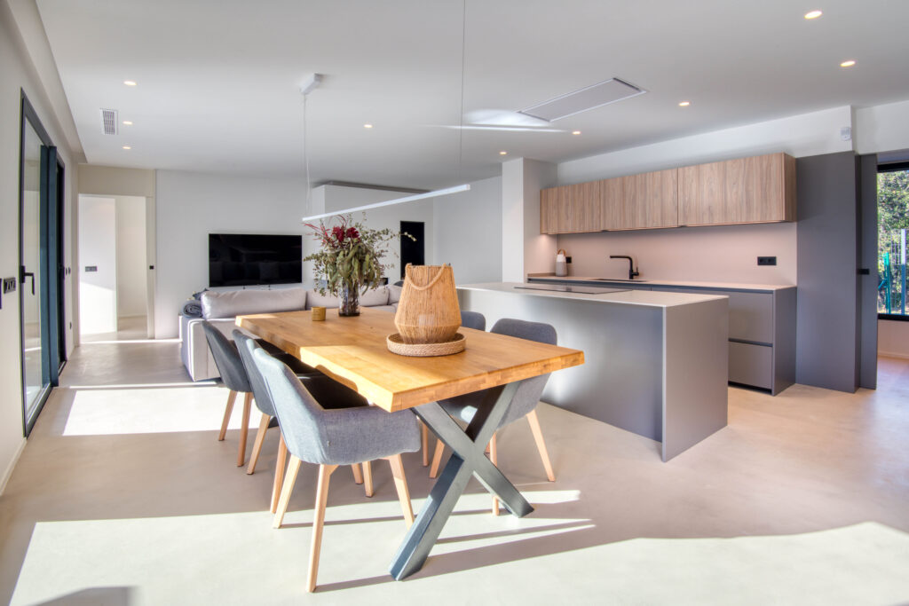 Suelo de microcemento en cocina y comedor de estilo moderno, mostrando un diseño de interiores continuo y arquitectura minimalista.
