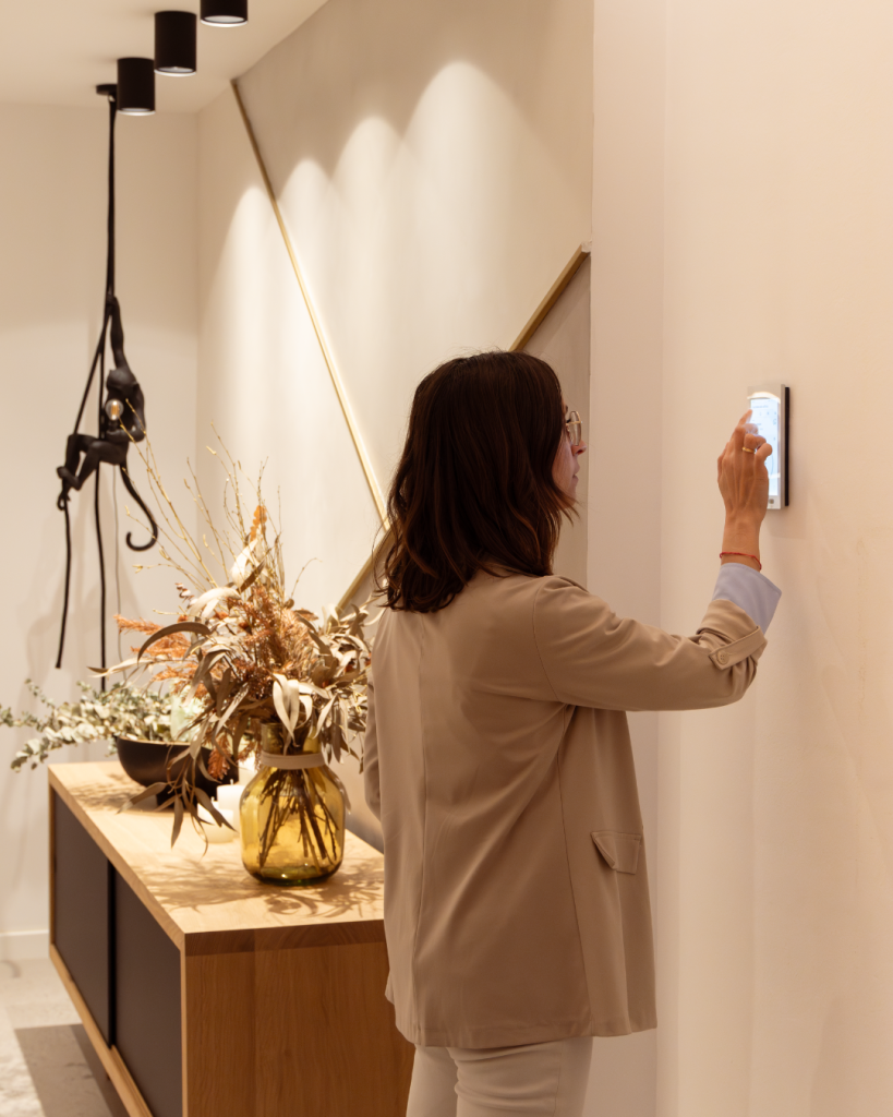 Persona regulando un sistema de domótica en una vivienda, control de iluminación y climatización integrado en el diseño arquitectónico del espacio.||