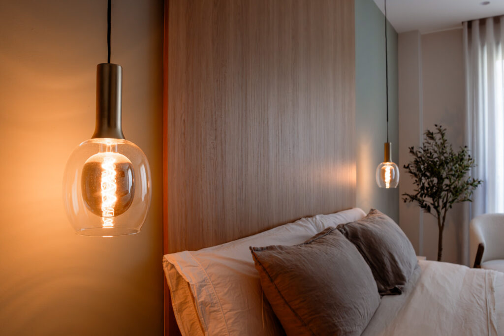 Iluminación en dormitorio con lámparas colgantes laterales, luz cálida pensada para crear un ambiente relajante y funcional en casa.
